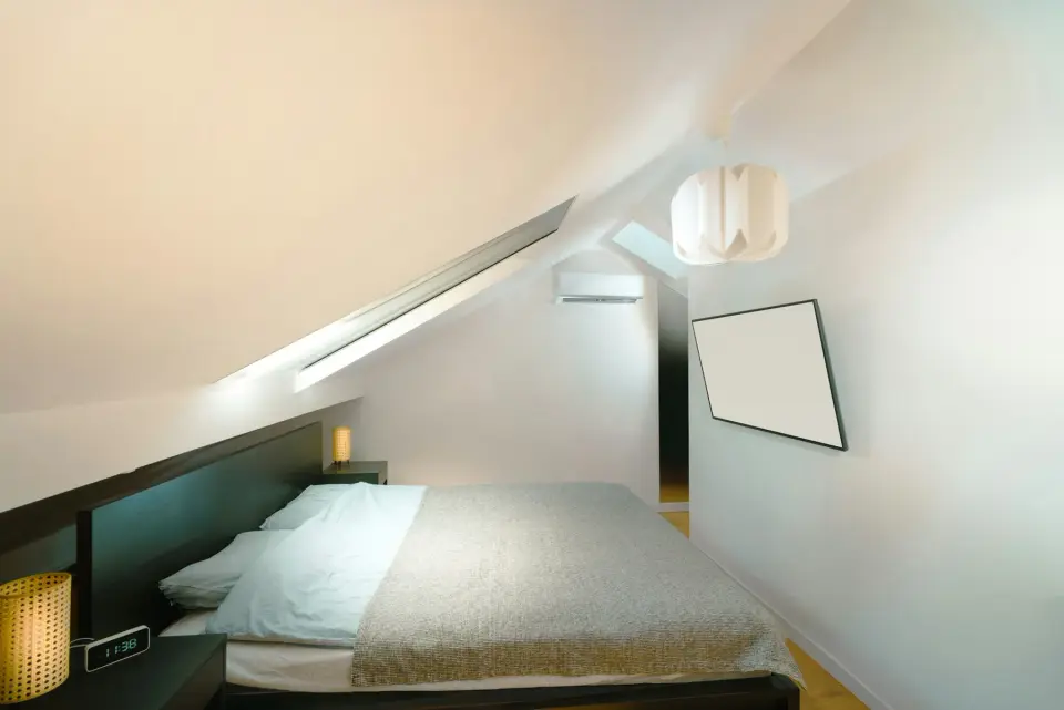 Afgewerkte zolderkamer met een bed onder het schuine dak en een dakraam